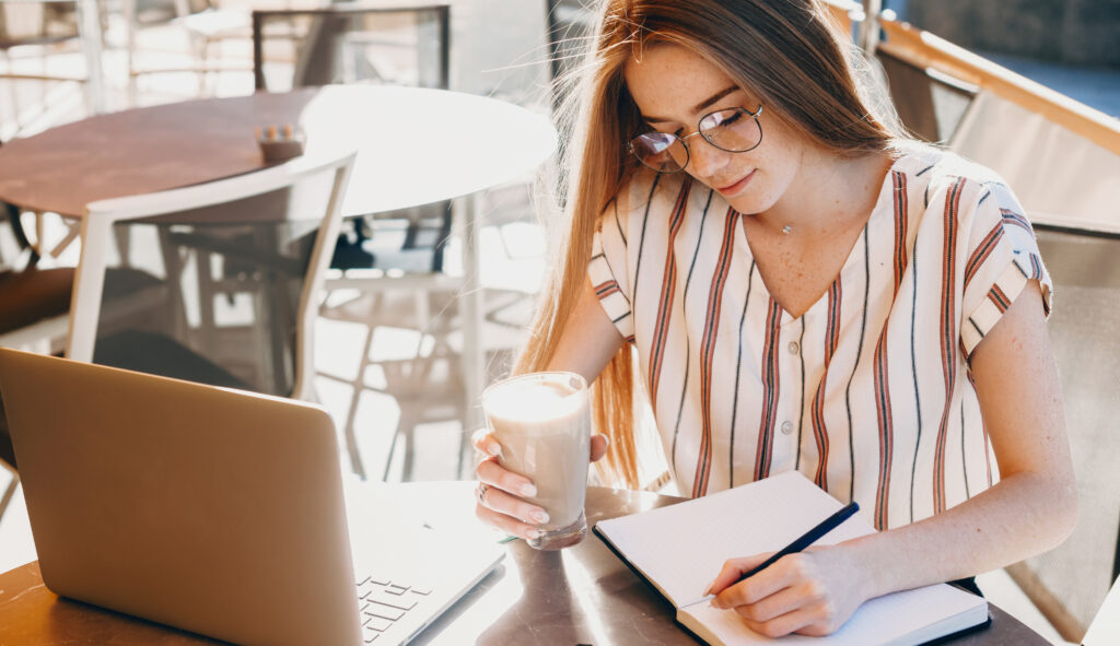 Woman writing and drinking coffee