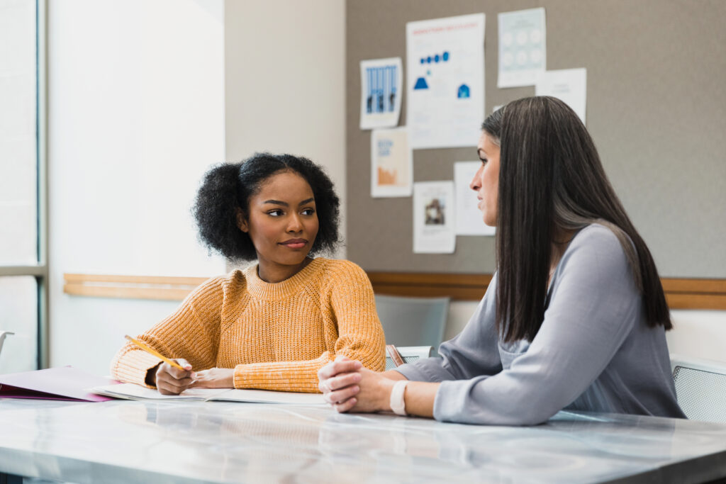 Teenage girl listens to mid adult female teacher